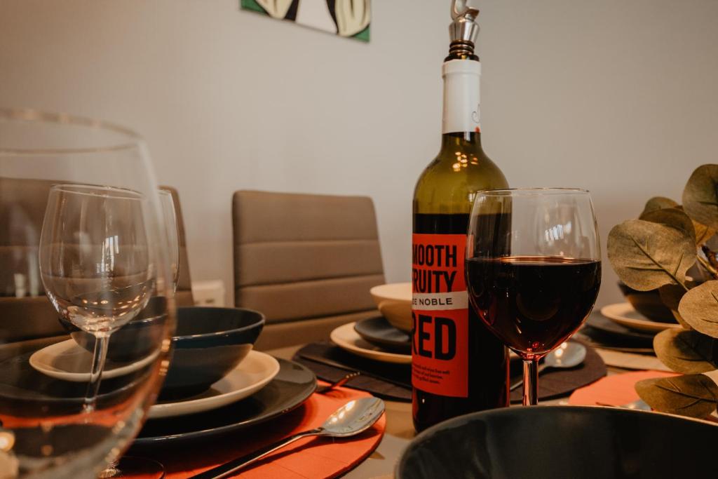 a bottle of wine sitting on a table with two glasses at Coyle House, 3 bed, super kings or twins, driveway, free wi-fi, pets, corporates welcome in Corby