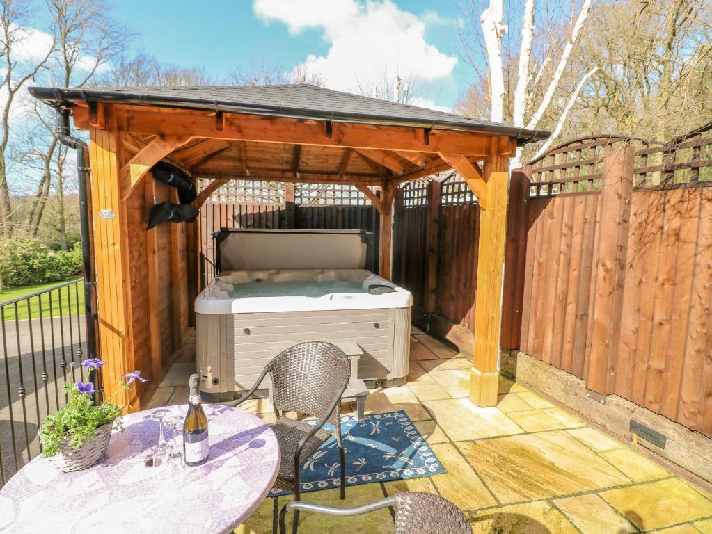 a barbecue under a wooden gazebo on a patio at Bluebell Cottage in Alfreton