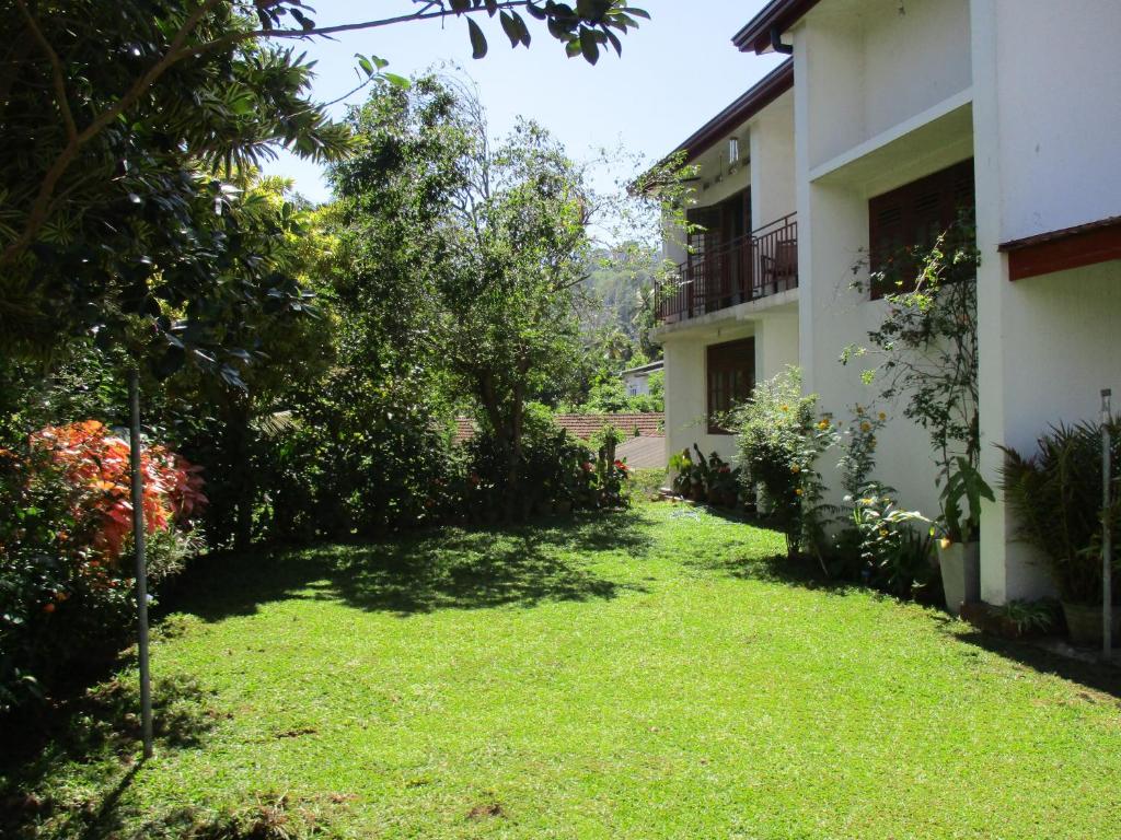 une cour à côté d'un bâtiment avec de l'herbe et des arbres dans l'établissement KOON COTTAGE, à Kandy
