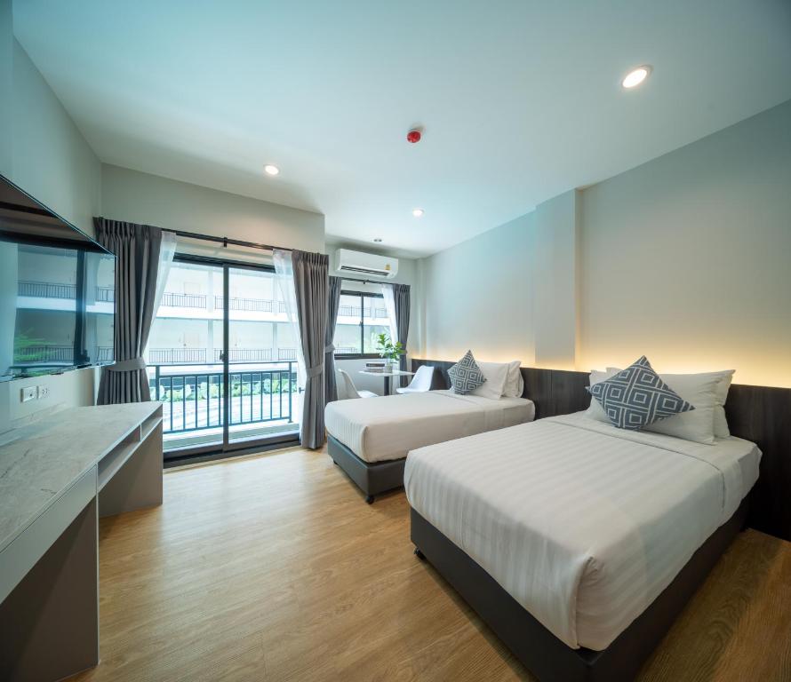 um quarto de hotel com duas camas e um sofá em College Haus Rangnam em Bangkok
