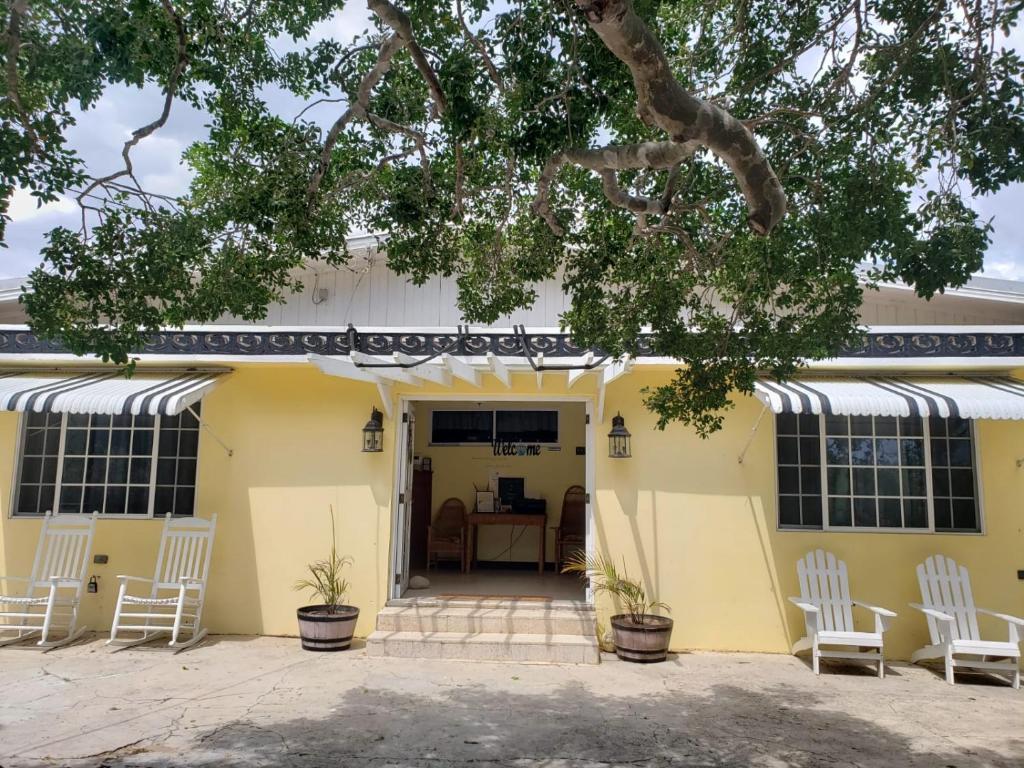 a yellow house with white chairs in front of it at Treasure Beach Inn and Bar in Treasure Beach