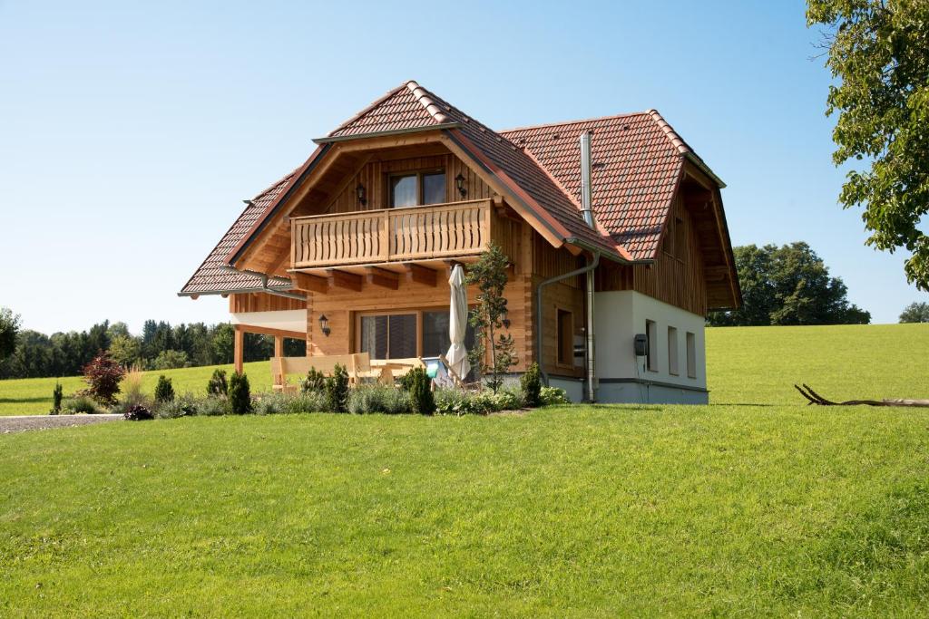 a log home with a deck on a green field at Ferienhaus Reisinger Promschhof in Semriach