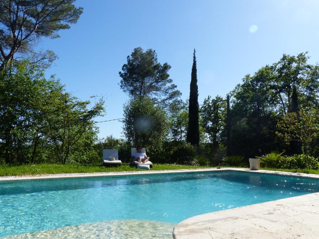 a person sitting in a chair next to a swimming pool at Ô Tilia d'Azur in Roquefort-les-Pins