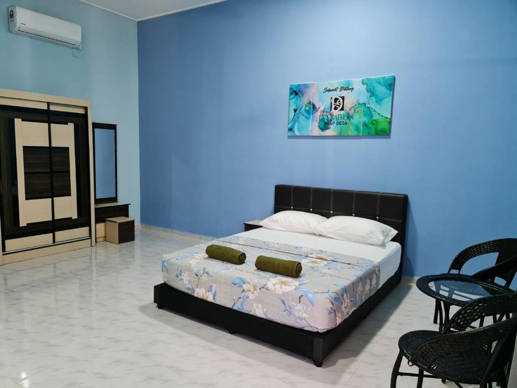a bedroom with a bed and chairs and a blue wall at D'EMBUN INAP DESA BESUT in Kampung Raja
