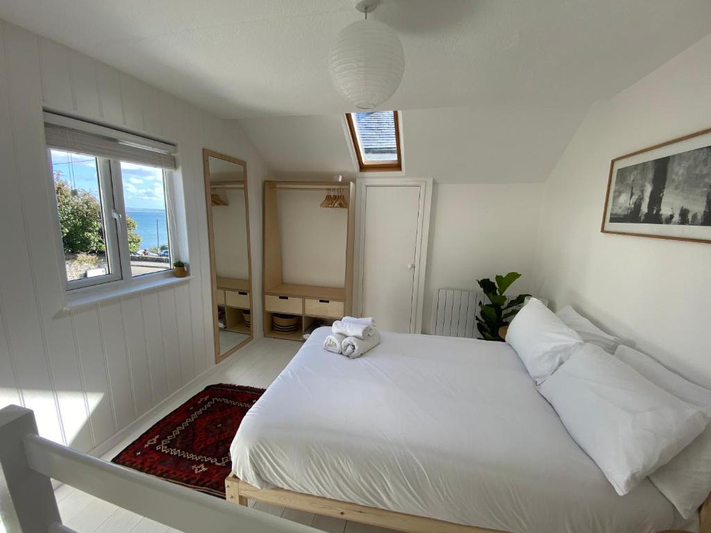 a bedroom with a white bed and a window at Cheerful one bedroom cottage in Mousehole. in Mousehole