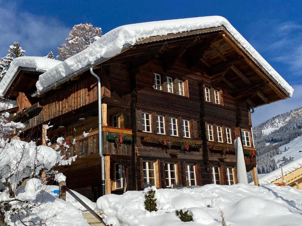 ein großes, schneebedecktes Holzgebäude in der Unterkunft Büehl Lenk in Lenk im Simmental