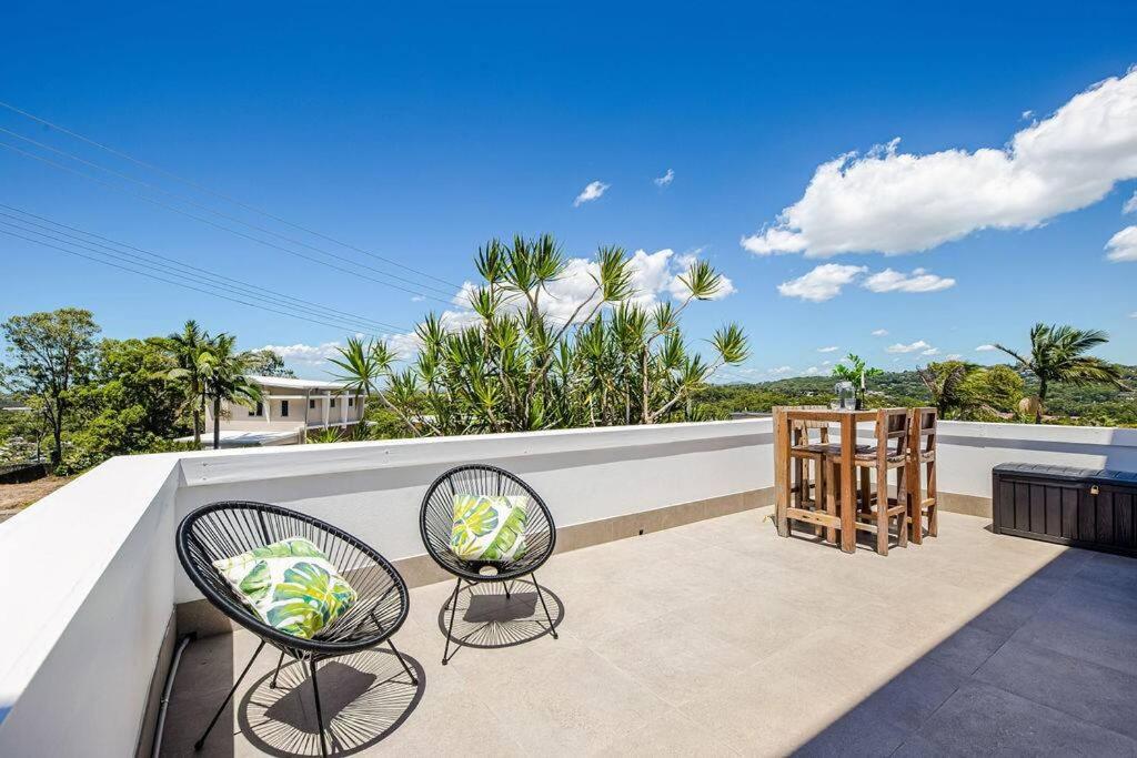 un patio con 2 sillas y una mesa en el balcón en Lovely 2bd Unit, Patio and views. Best weekly rate, en Alexandra Headland