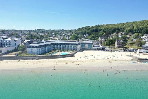 une plage avec un groupe de personnes dans l'eau dans l'établissement Résidence des sables blancs, à Douarnenez