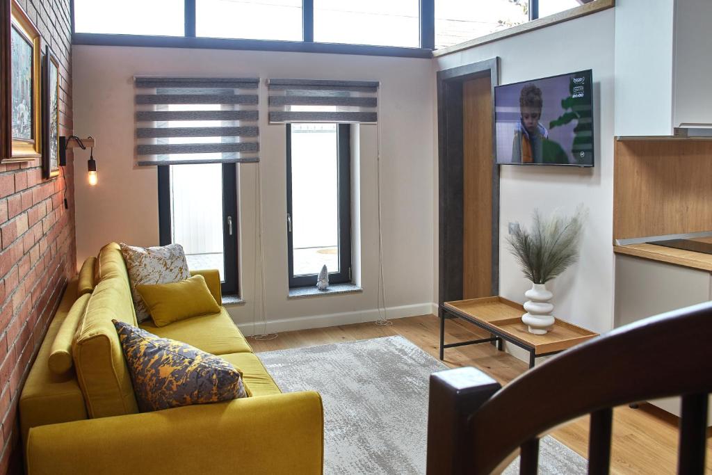 ein Wohnzimmer mit einem gelben Sofa und 2 Fenstern in der Unterkunft Apartament CITY la casa PIANO HOUSE ,cu parcare in Alba Iulia