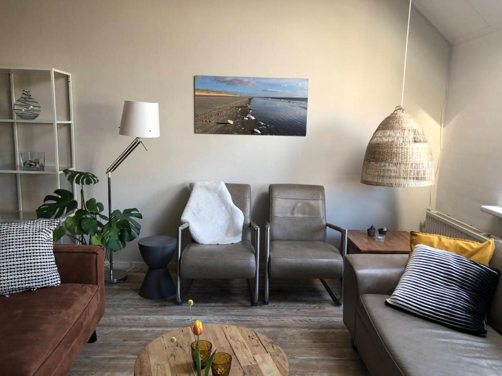 uma sala de estar com um sofá, cadeiras e uma mesa em Naar Zee op Ameland em Buren
