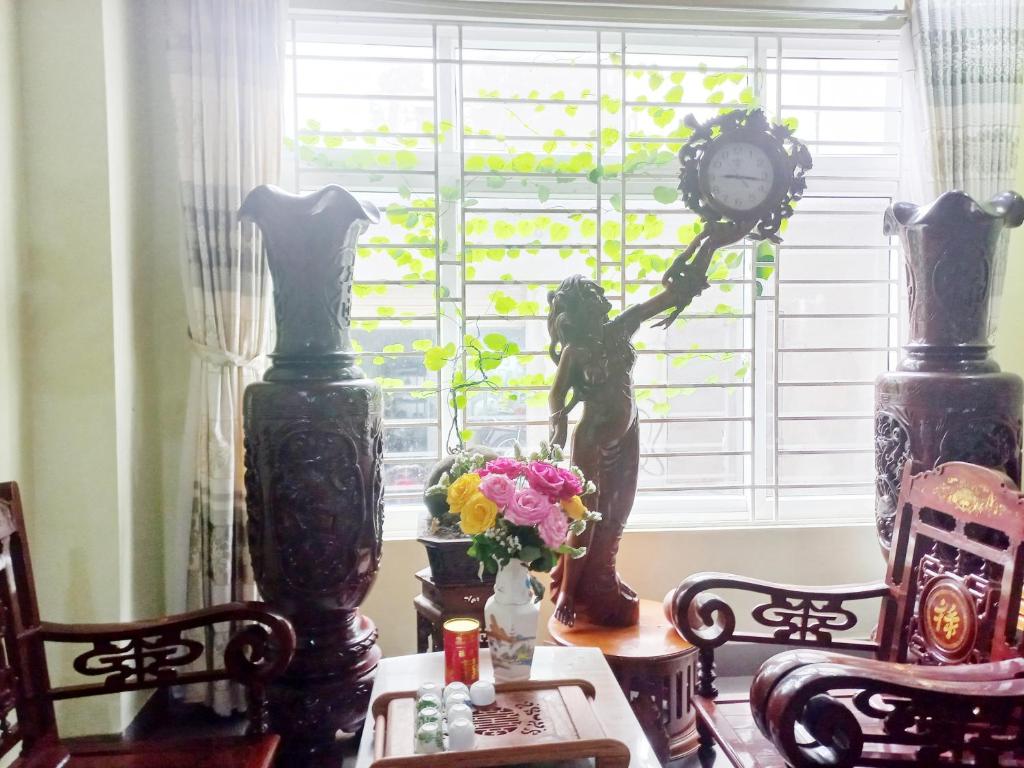 una estatua de una persona sosteniendo un reloj en una ventana en HAI DANG HOTEL en Xóm Ðé