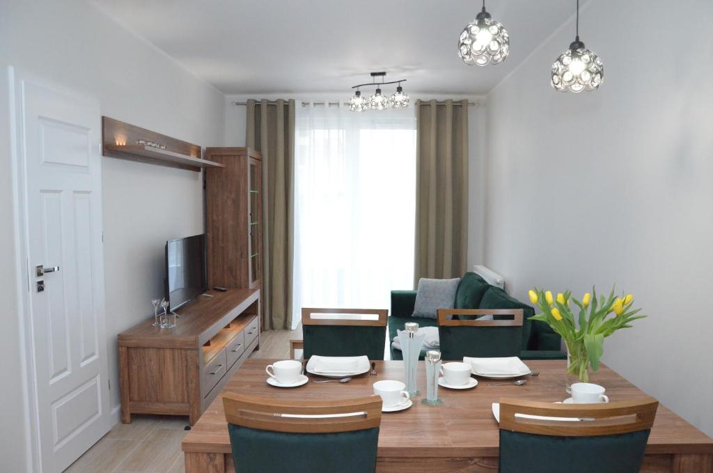 - un salon avec une table, des chaises et une télévision dans l'établissement Apartament Luna Baltic Marina Residence, à Kołobrzeg