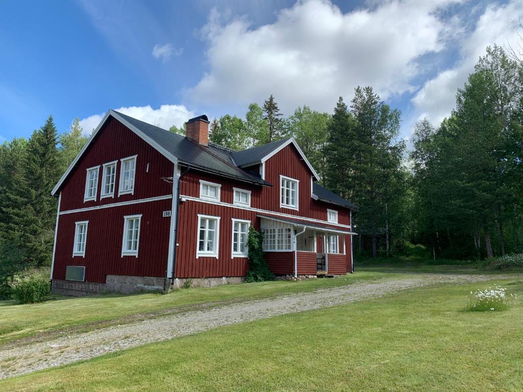 a red barn with white windows in a field at Linsell nyrenoverad lägenhet in Linsell