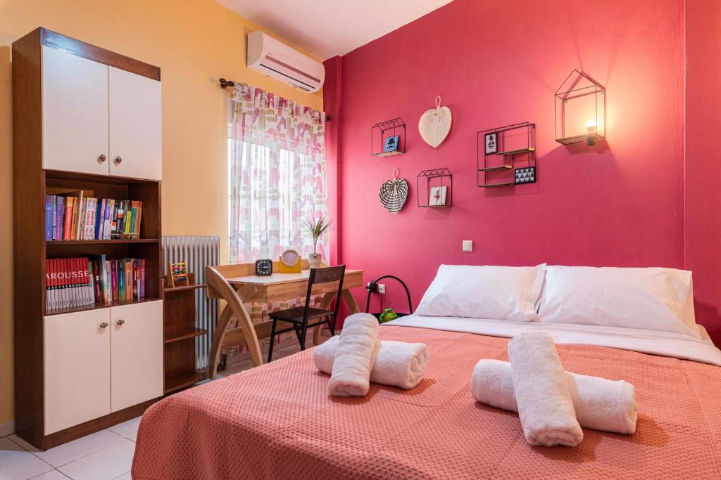 a bedroom with a pink wall with a bed and a table at Blossom in Ierapetra