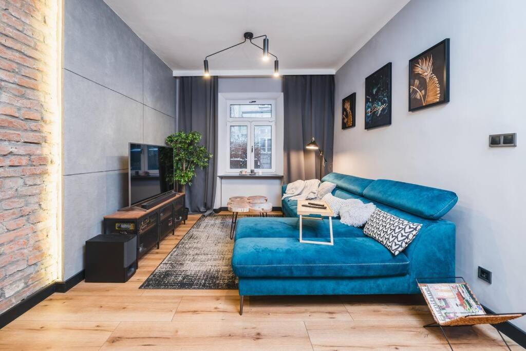 sala de estar con sofá azul y pared de ladrillo en Zender Kazimierz Apartment, en Cracovia