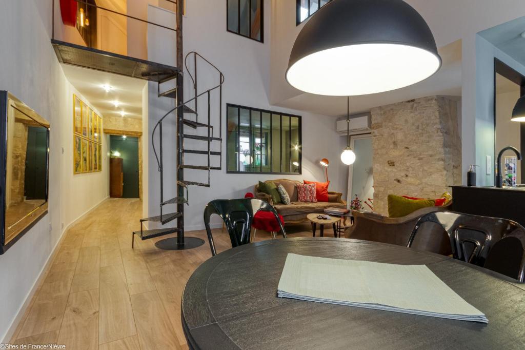 a living room with a table and a spiral staircase at Au Noeud Vert Chambres d'hôtes in Nevers