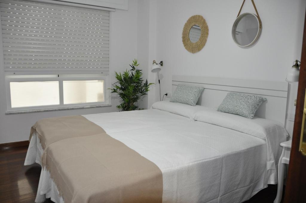 a white bedroom with a large bed and a window at Alojamiento Santa Maria II in Milladoiro