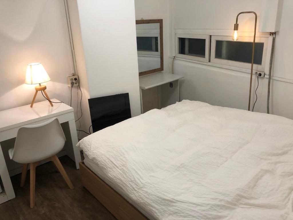 1 dormitorio con cama, escritorio y lámpara en Hostel Metro, en Seúl