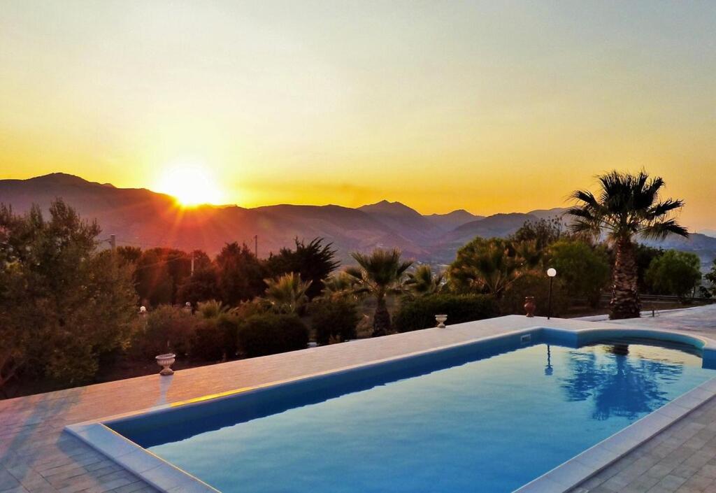 una piscina con tramonto sullo sfondo di Villa Bella Vista a Palermo