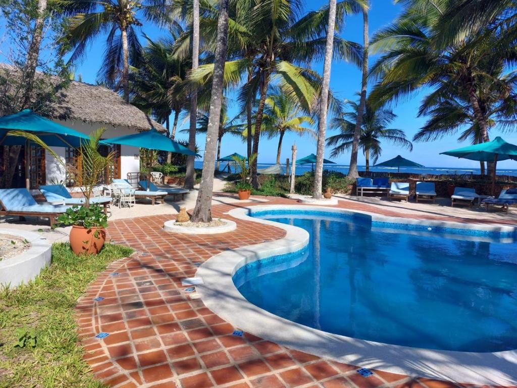 a swimming pool at a resort with palm trees at Asha Boutique Hotel in Diani Beach