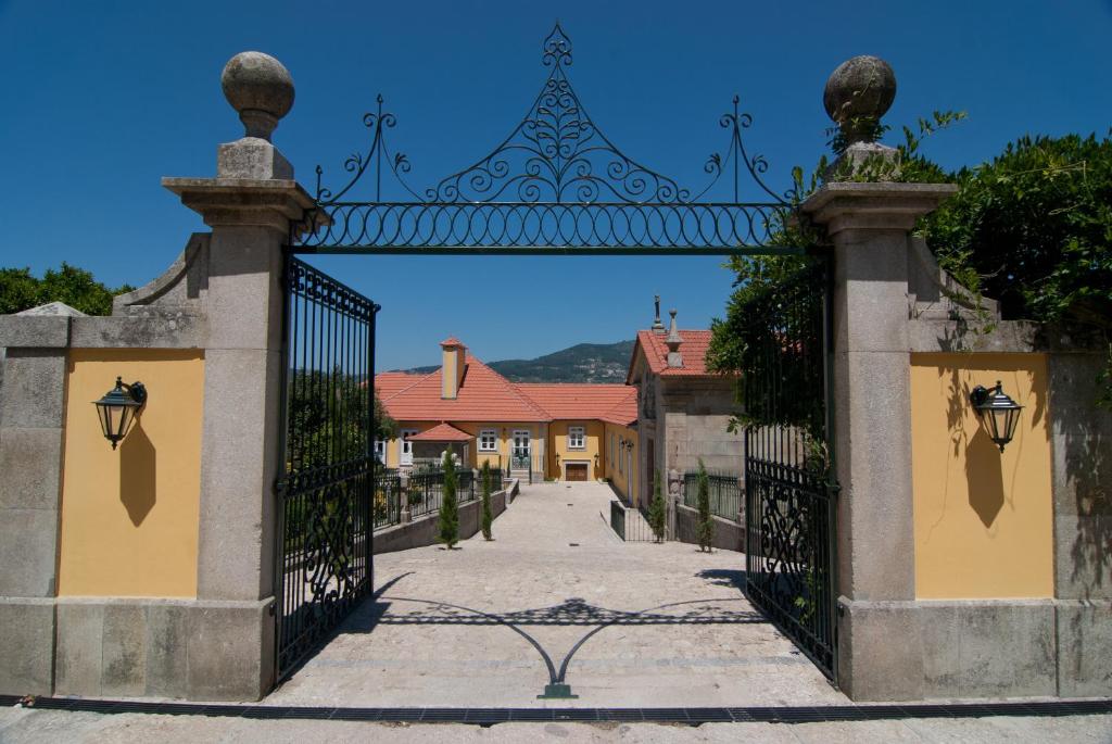 an ornate gate to a street with a house at Quinta do Outeiro in Resende