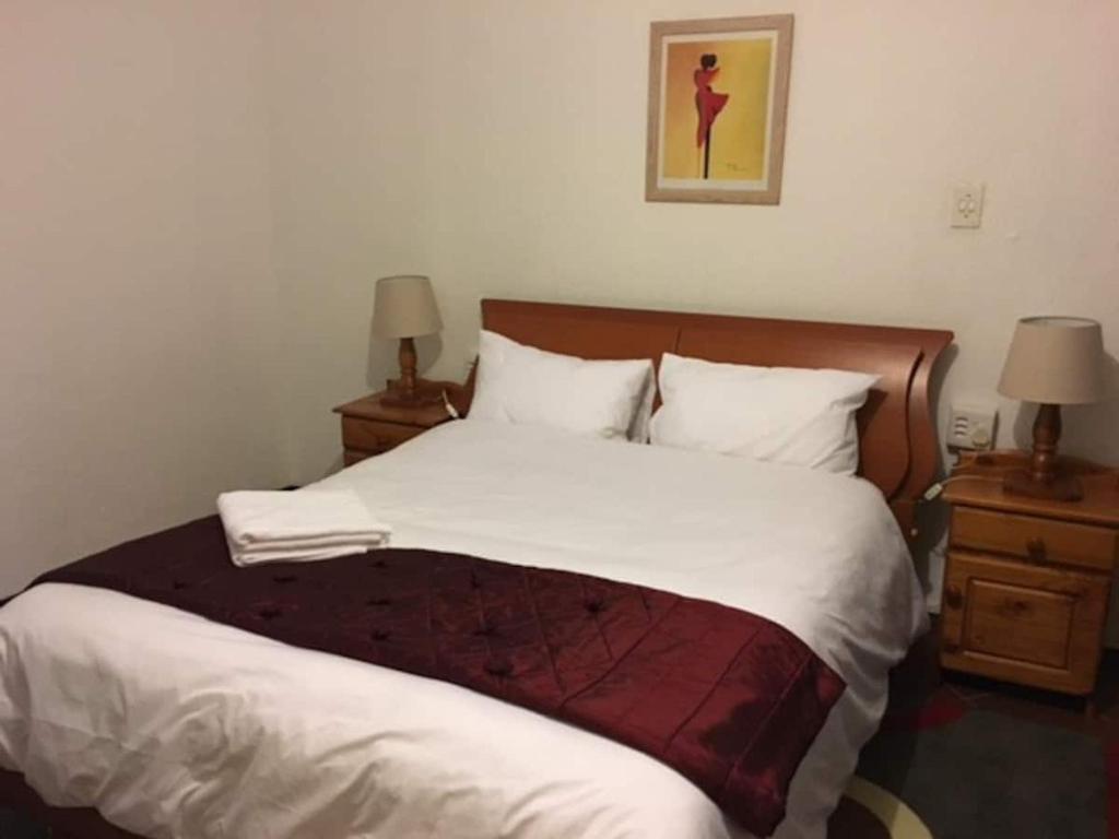 Private and cozy في Sandton: غرفة نوم بسرير كبير مع مواقف ليلتين