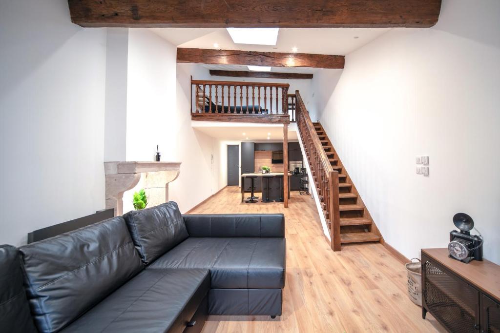 ein Wohnzimmer mit einem schwarzen Ledersofa und einer Treppe in der Unterkunft Loft au coeur du centre ville in Mâcon