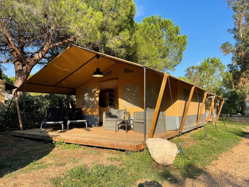 a large tent with a deck in a field at Budget Glamping Safaritent - Mas de Mourgues in Vauvert