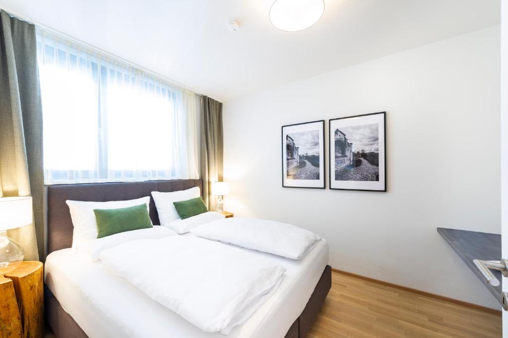 sypialnia z dużym łóżkiem z białymi i zielonymi poduszkami w obiekcie Apartments am Kalvarienberg w Grazu