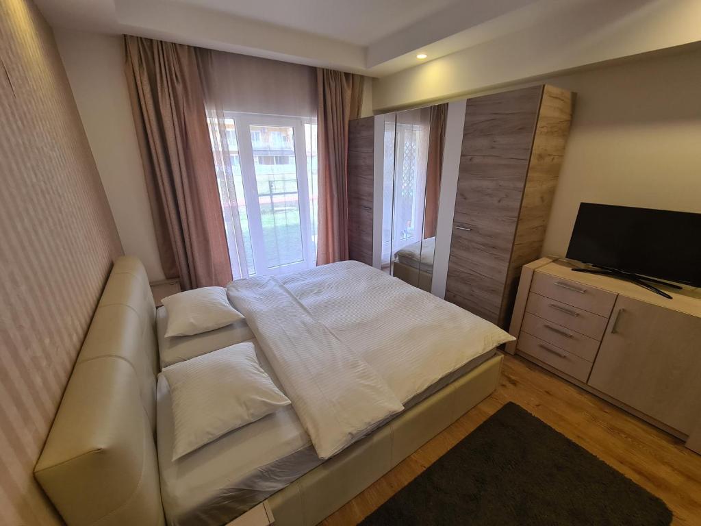 ein Schlafzimmer mit einem Bett mit einem Sofa und einem TV in der Unterkunft COSMOPOLIS in Ştefăneştii de Jos