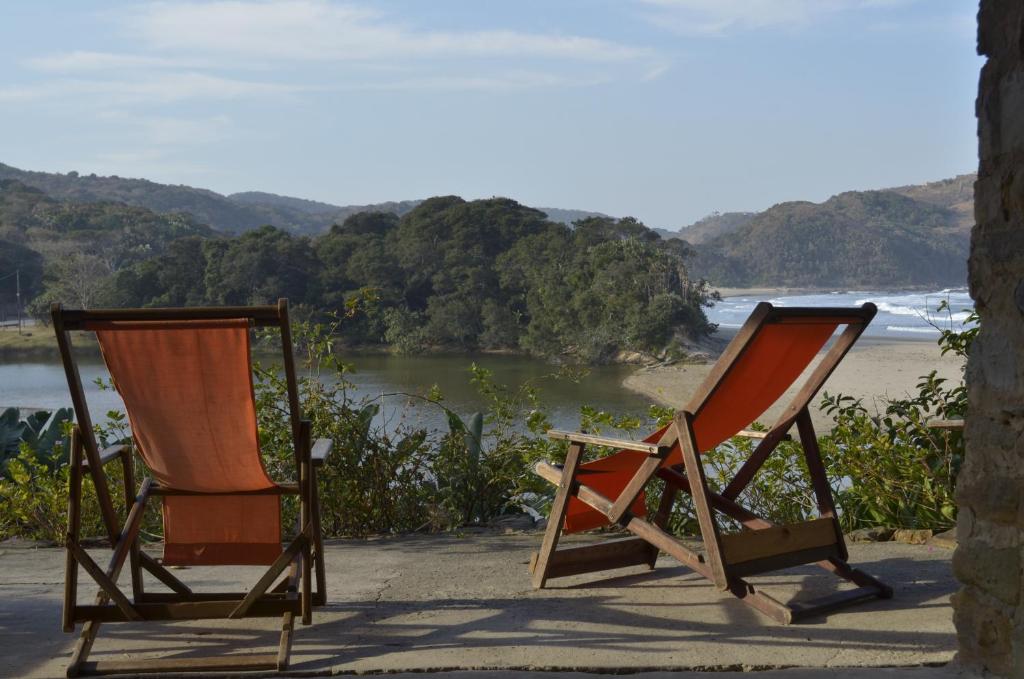 two chairs sitting on a beach near the water at The Lodge on the Beach in Port St Johns