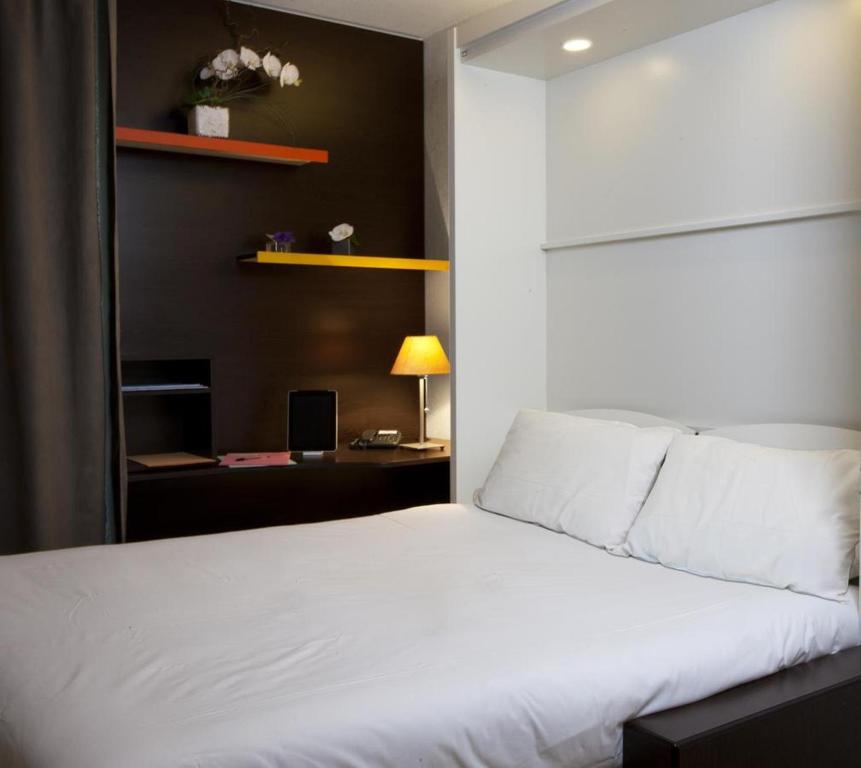 a bedroom with a white bed and a desk at At Home Appart Hotel in Toulouse