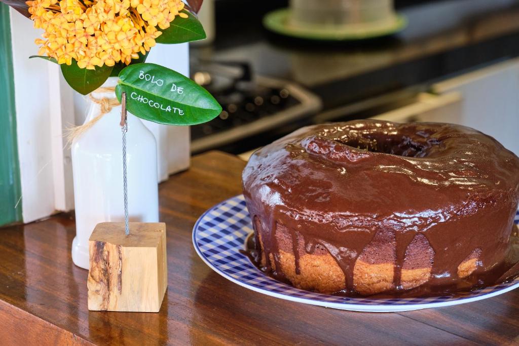 a chocolate cake on a table next to a vase of flowers at Boutique Hotel Carpe Diem in Paraty