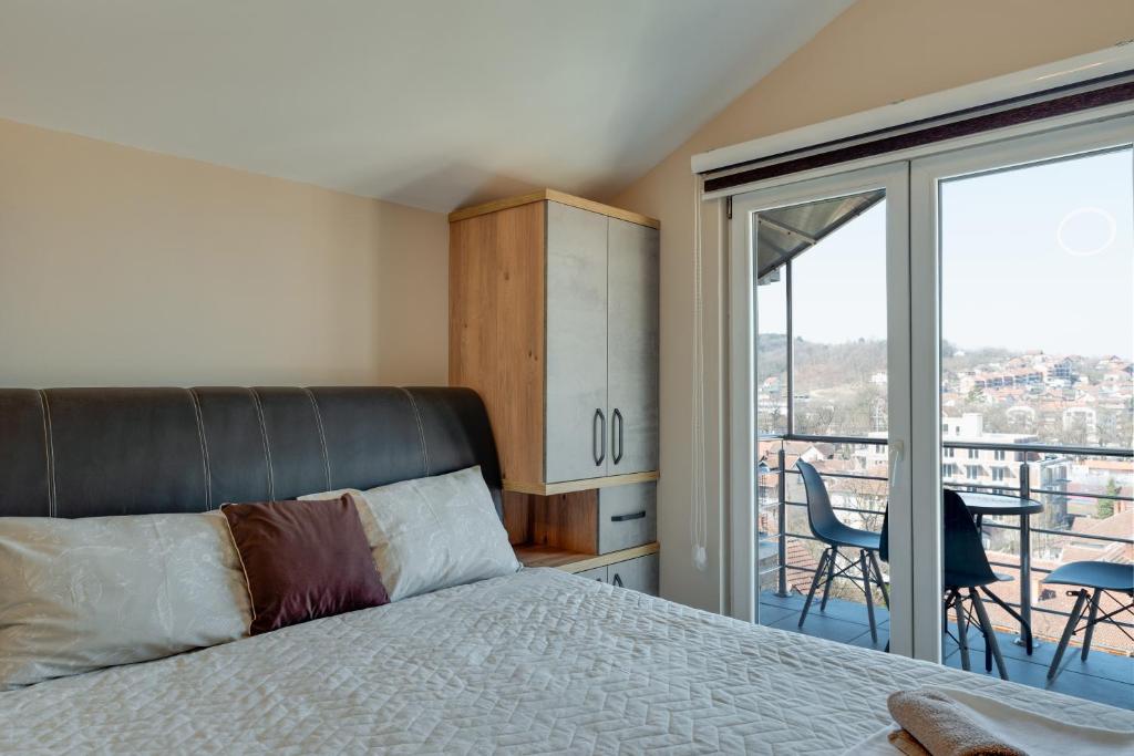 a bedroom with a bed and a balcony at IN LUX APARTMAN in Vrnjačka Banja