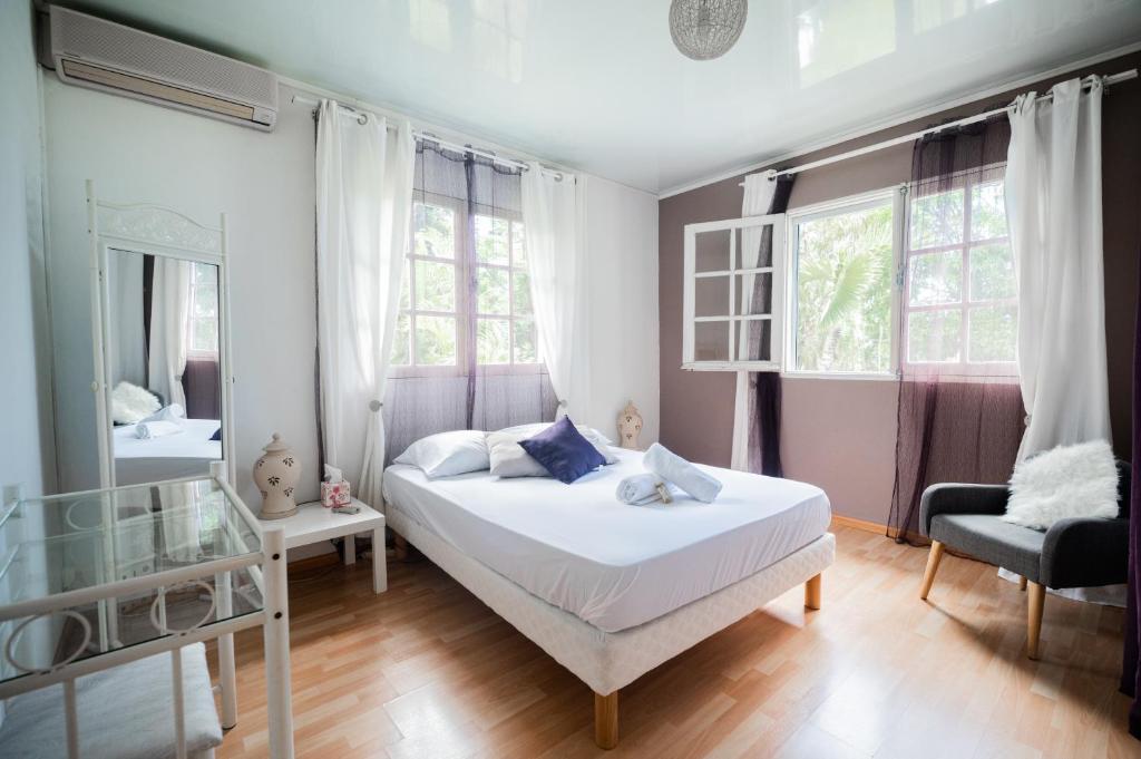 um quarto com uma cama, uma cadeira e janelas em La Kaz Pepper em Saint-Denis