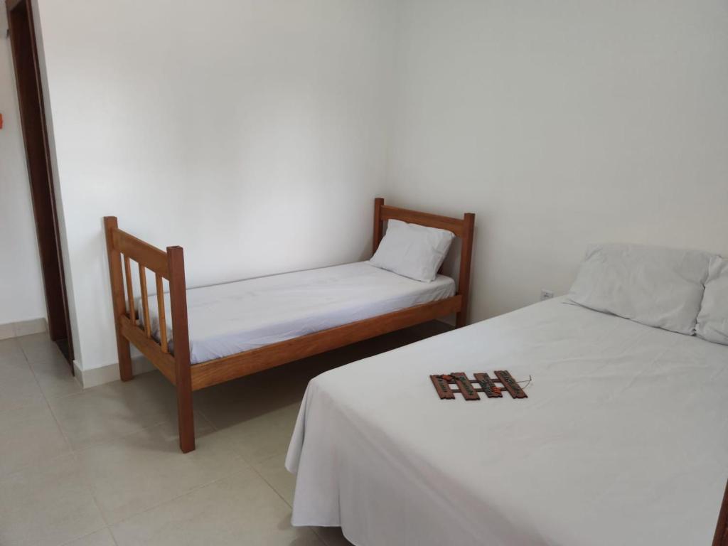 a bedroom with two beds and a bed and a chair at Pousada Sonho Meu in Itaúnas