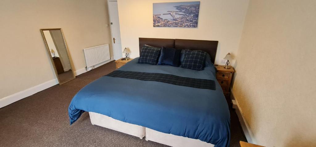 um quarto com uma cama grande com lençóis e almofadas azuis em Harbour bridge, Camps bar em Wick