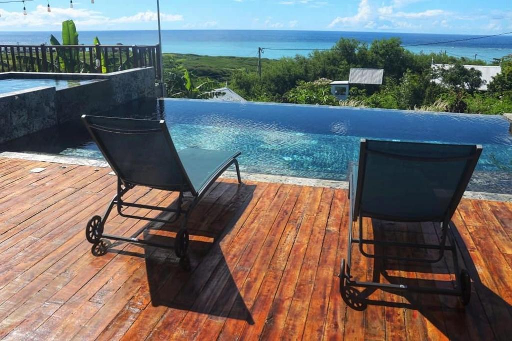 - deux chaises assises sur une terrasse à côté d'une piscine dans l'établissement Residence Foulsafat, à Rodrigues Island