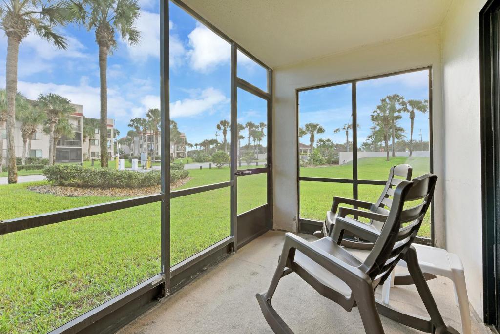 two chairs sitting on a porch looking out at the grass at Ocean Village Club N14, 1 Bedroom, Sleeps 4, Heated Pool, Pet Friendly, WiFi in St. Augustine