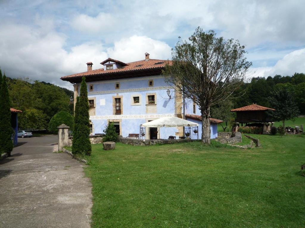 ein großes weißes Haus mit einem Baum im Hof in der Unterkunft Hotel Rural Sucuevas in Mestas de Con