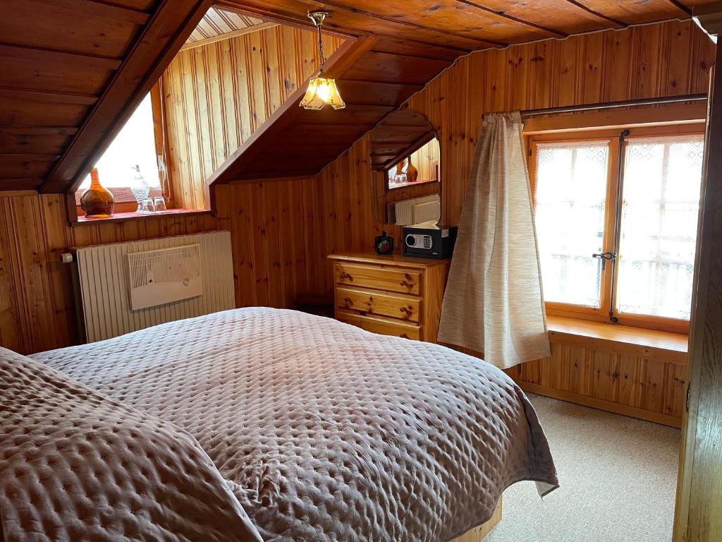 um quarto com uma cama num quarto com paredes de madeira em Harmony House em Salvan