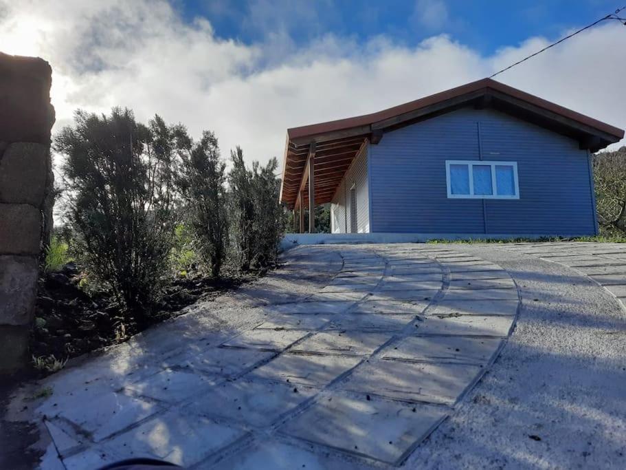 a blue house with a driveway in front of it at Casa de madera El jardín de Tara in Tiñor