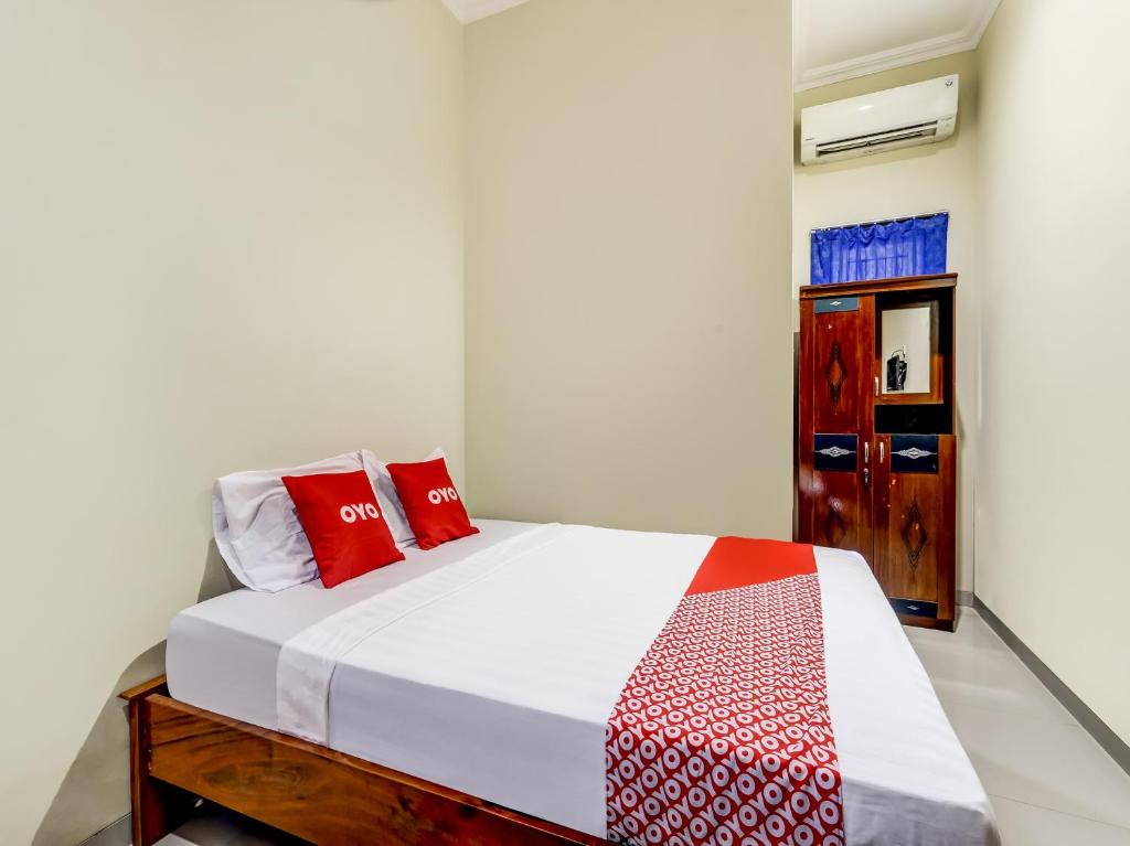 a bedroom with a bed with red pillows on it at Super OYO 90927 Homestay Tentrem 2 in Pati