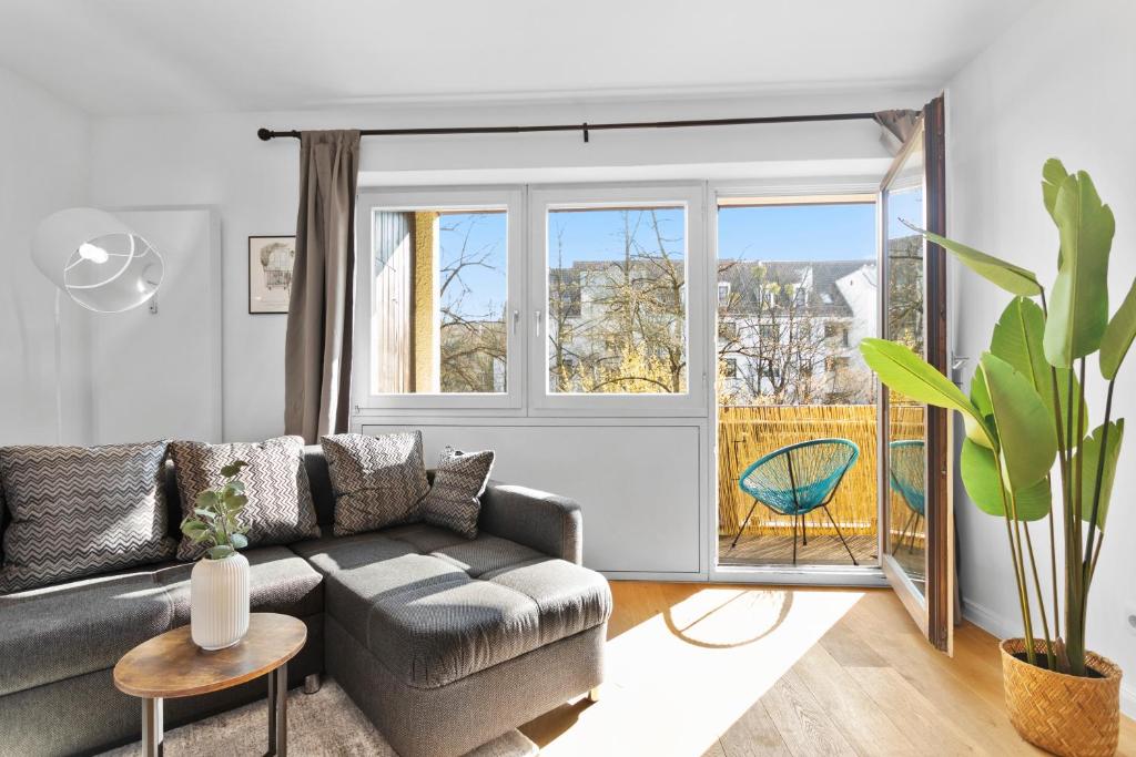 a living room with a couch and a large window at Flatista Homes - Hirschgarten in Munich