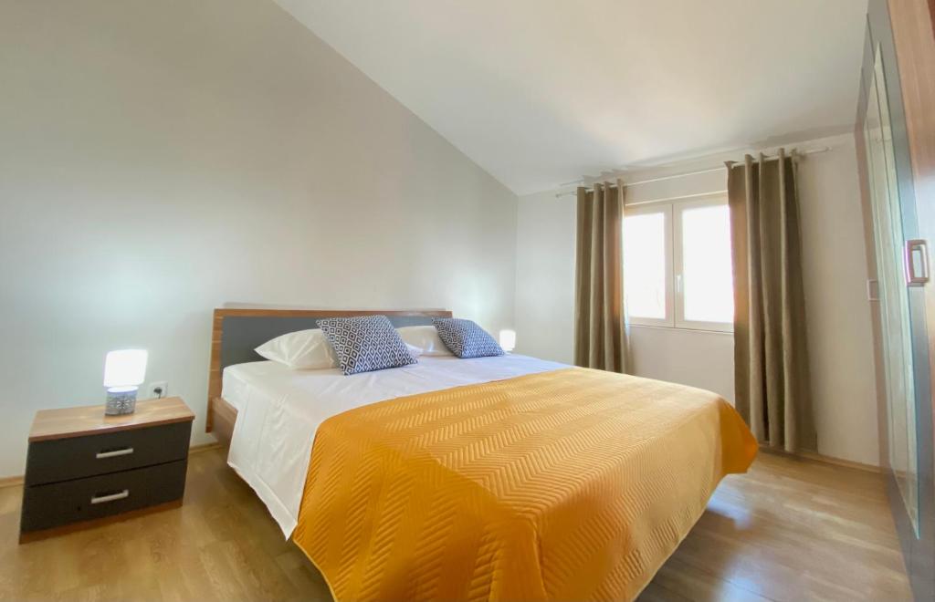 1 dormitorio con 1 cama grande con manta amarilla en Apartment Kantun en Skradin