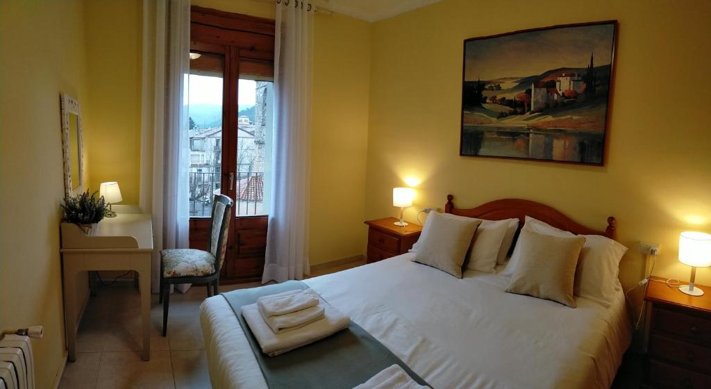 ein Schlafzimmer mit einem großen weißen Bett und einem Fenster in der Unterkunft Casa María, ático con vistas y parking in Sant Joan de les Abadesses