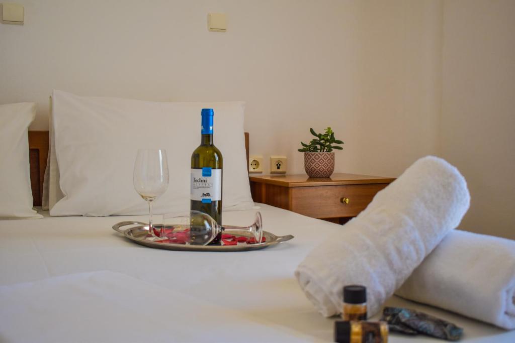 a bottle of wine and a plate of food on a bed at Giannis & Maria Gramvousaki Apts in Agia Marina Nea Kydonias
