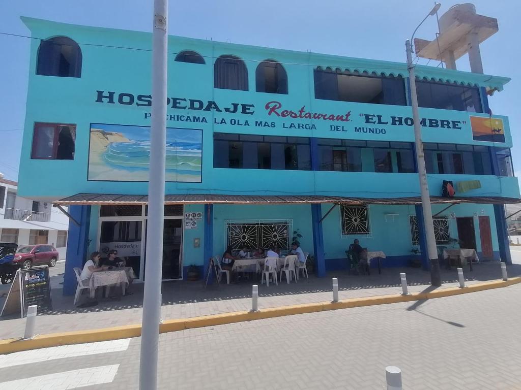 un edificio azul con mesas y sillas delante de él en Hospedaje Restaurante El Hombre, en Puerto Chicama