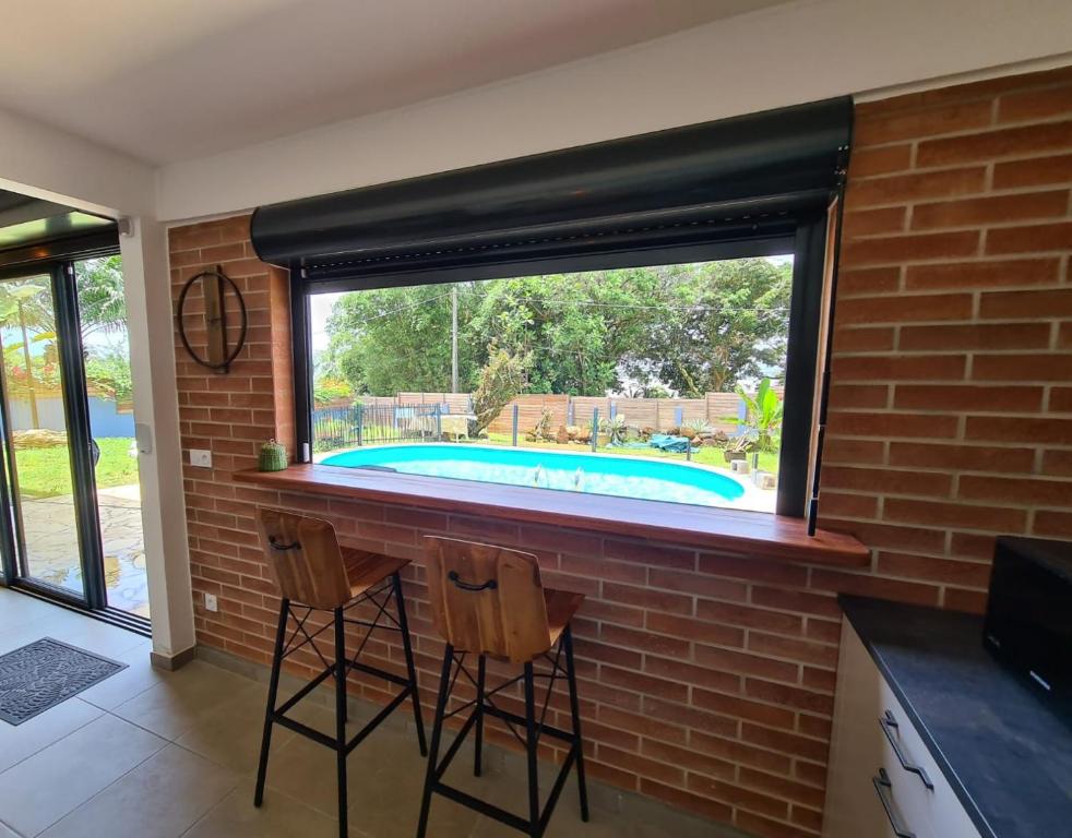 una cocina con un bar con una piscina a través de una ventana en Shikoa Sobole - Le Morpho et l'Ara en Montjoly