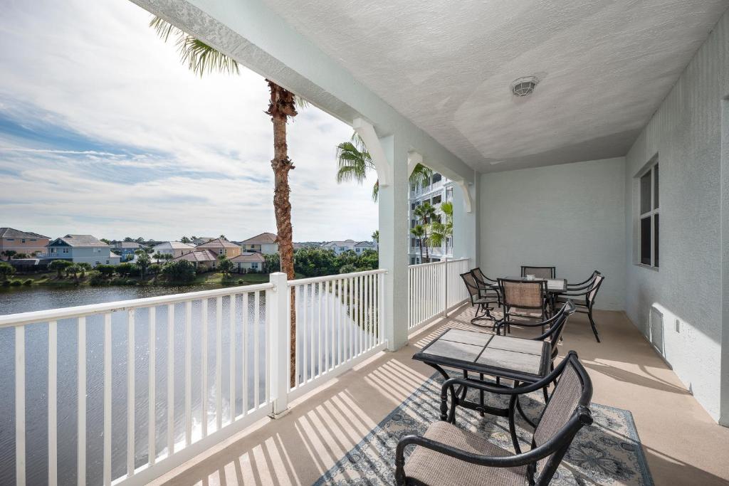 a balcony with tables and chairs and a palm tree at 1033 Cinnamon Beach, 3 Bedroom, Sleeps 8, 2 Pools, Elevator, Pet Friendly in Palm Coast